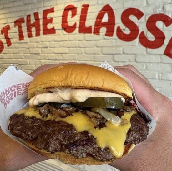 A hand holding a burger
Description automatically generated