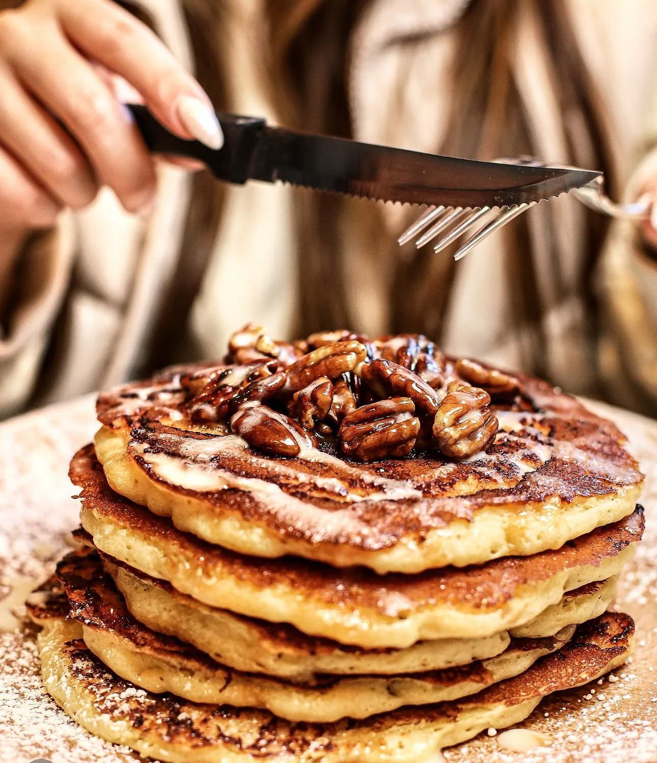 A person cutting a stack of pancakes with a knife and fork
AI-generated content may be incorrect.