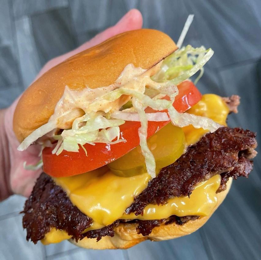 A hand holding a cheeseburger AI-generated content may be incorrect.